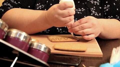 Thick female hand draws icing on gingerbread house Stock Footage 101818225