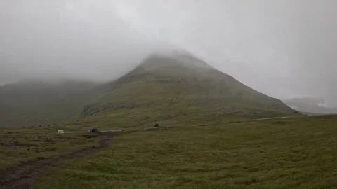 Thick fog rolling over green mountain on Eysturoy, Faroe Islands Stock Footage 340005298