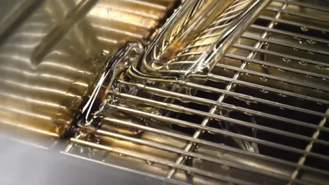 Thick Golden Liquid Pouring Over Metal Conveyor Grid in Factory Production Line Stock-Footage 343028135