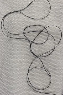 Thick gray thread randomly lying on rough fabric. Stock Photos