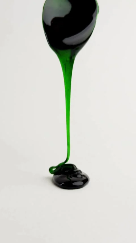 Thick green liquid dripping from spoon onto white surface Stock Footage 331775195