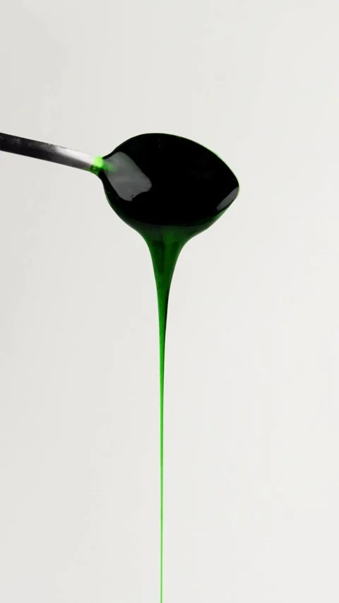 Thick green liquid drips slowly from a silver spoon Video stock 331775080