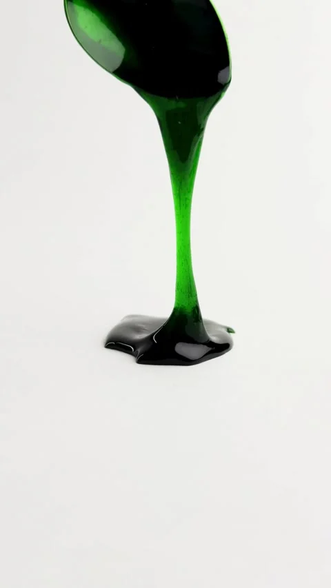 Thick green liquid drips from spoon onto white surface Vídeos de archivo 331774724
