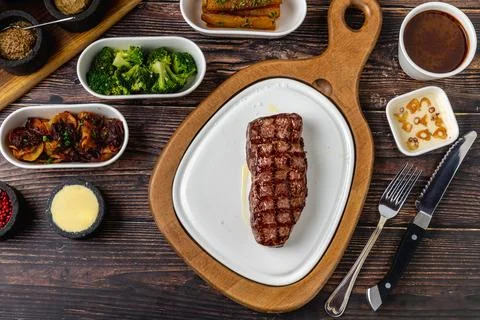 Thick grilled beef steak served on a rustic wooden board Stock Photos