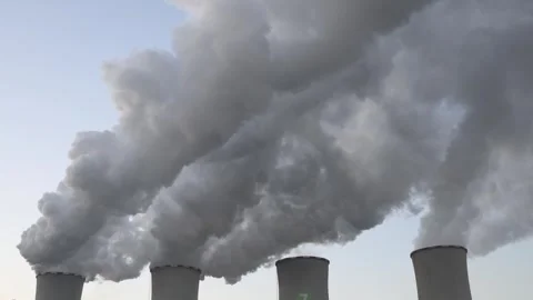 Thick industrial smoke rises from large cooling towers filling the pale  Stock Footage 321650811