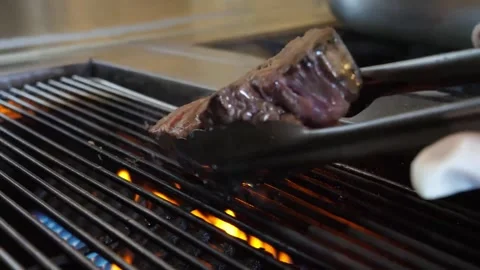 Thick Juicy Beef Steak Grilling on Hot BBQ Grill with Roaring Flames Stock Footage 337677611