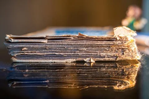 A thick large, ragged, old torn book on a transparent glass table, scripture  Stock Photos