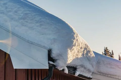 Thick layer of heavy snow drift on the roof of a cabin. Stock Photos