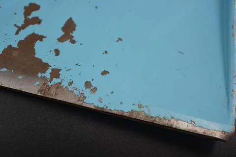A thick layer of painted metal from which blue paint has peeled off. Stock Photos