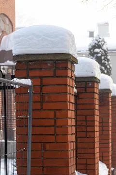 A thick layer of snow has fallen on the edge of the fence. Stock Photos