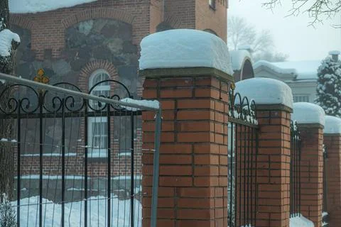 A thick layer of snow has fallen on the edge of the fence. Stock Photos