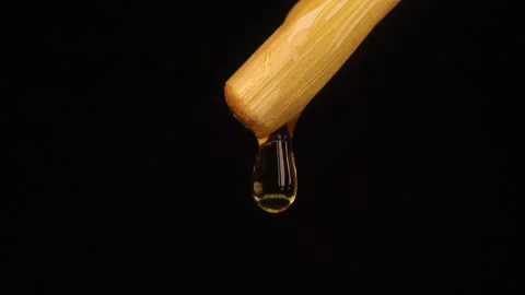 Thick liquid drop of oil or honey falling over black background. Healthy food Stock Footage 246119786