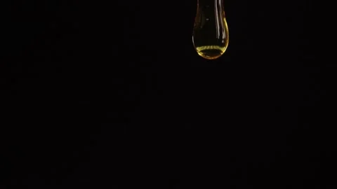 Thick liquid drop of oil or honey falling over black background. Healthy food Stock Footage 246140894