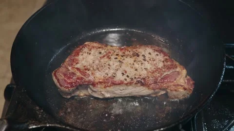 Thick NY strip steak sears in a hot cast iron skillet Stock Footage 327240238
