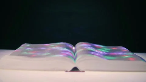 On thick open book colored light spots move across the pages Stock Footage 313148406