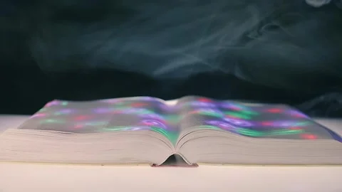 On thick open book colored light spots move across the pages Stock Footage 313224623