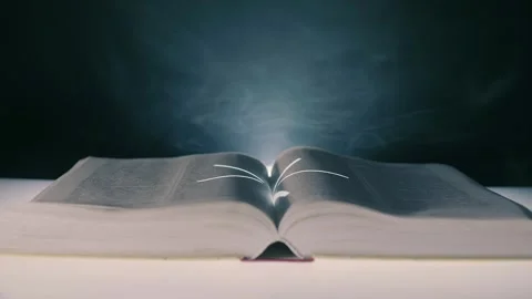 On thick open book white light rays move across the pages Stock Footage 313148518