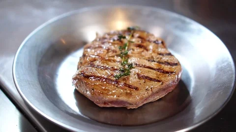 Thick piece of beef steak meet cooked on grill pan resting on steel plate in Stock Footage 105895618