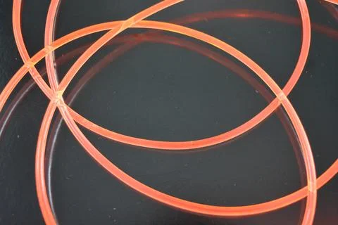 Thick plastic flexible glowing wires with a soft red, cherry-colored glow. Stock Photos