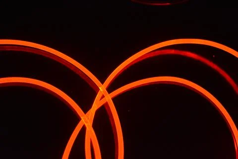 Thick plastic flexible glowing wires with a soft red, cherry-colored glow. Stock Photos