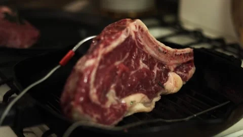 Thick raw beef steak with bone cooking on cast iron grill pan Stock Footage 340563131