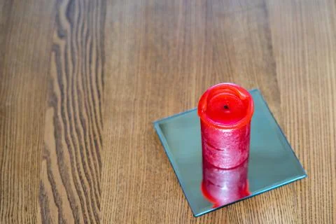 A thick red candle stands on the table. Side view. Place for text Stock Photos