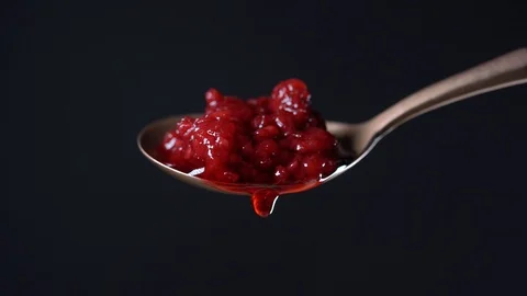 Thick red raspberry jam dripping from the spoon, one drop, on black backgroun Stock Footage 118638830