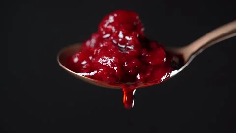 Thick red raspberry jam dripping from the spoon, one drop, on black background Stock Footage 137286803