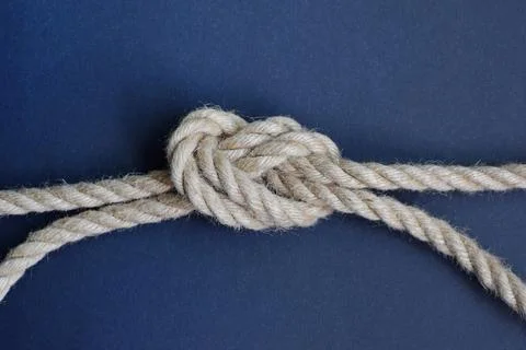 Thick rope knot on blue background. Hemp rope with knot. Foto stock
