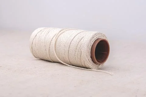 A thick rope is wound on a plastic spool and rests on the fabric. Stock Photos