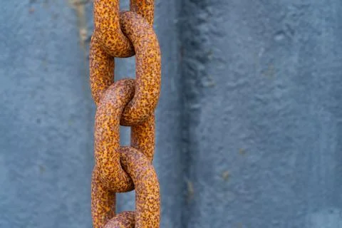 A thick rusty orange chain in front of blue background - security concept Stock Photos
