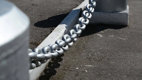 A thick silvery chain close to the asphalt is swinging with a strong wind Stock Footage 88528518