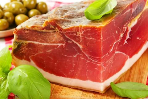 Thick sliced cured ham with olives and basil Stock Photos