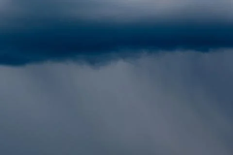 Thick storm clouds stretch across the sky with a visible curtain of rain falling Foto stock