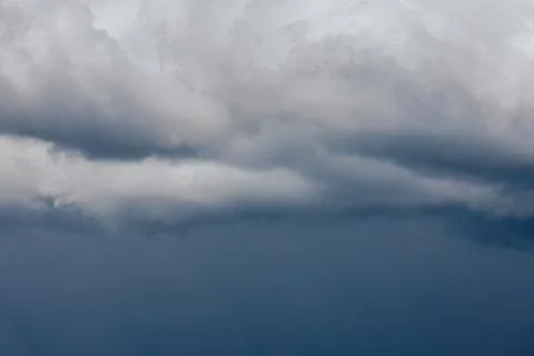 Thick storm clouds stretch across the sky with a visible curtain of rain falling Foto stock