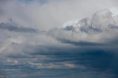 Thick storm clouds stretch across the sky with a visible curtain of rain falling Stock Photos