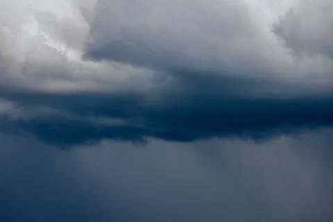 Thick storm clouds stretch across the sky with a visible curtain of rain falling Foto stock