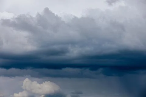 Thick storm clouds stretch across the sky with a visible curtain of rain falling Foto stock