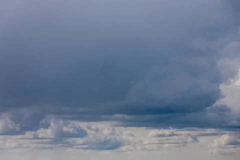 Thick storm clouds stretch across the sky with a visible curtain of rain falling Stock Photos