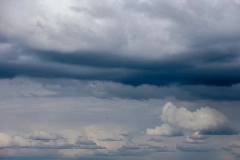 Thick storm clouds stretch across the sky with a visible curtain of rain falling 스톡 사진