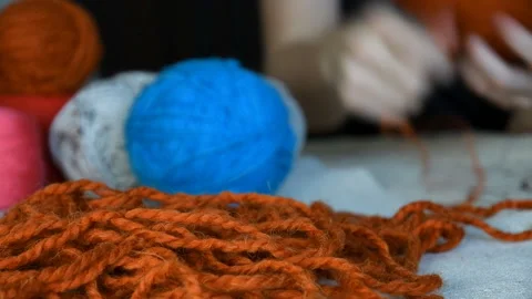 Thick terracotta wool yarn wrapped in a ball blurry hands in the background Stock Footage 137312793
