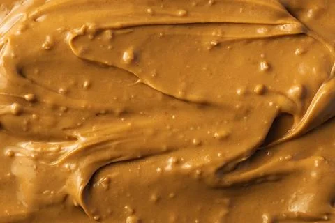 Thick texture of peanut butter with small nut pieces, evenly spread in a Stock Photos