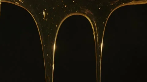 Thick viscous jets of engine synthetic oil in gold colour on a black background. Stock Footage 309952070