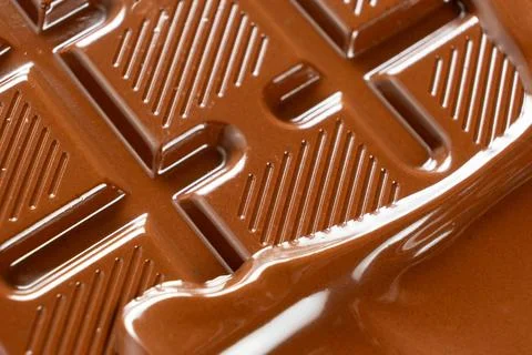 Thick warm chocolate waves flooding over solid chocolate bar close up Stock Photos