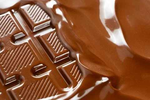 Thick warm chocolate waves flooding over solid chocolate bar close up Stock Photos