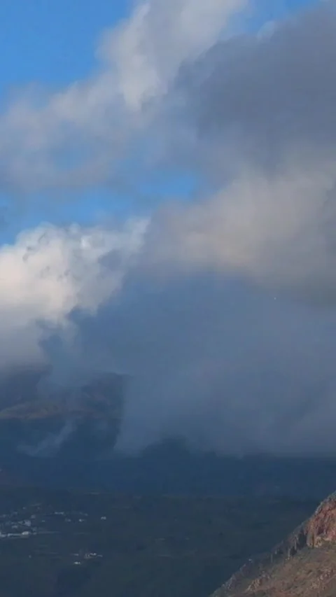 Thick white and gray clouds quickly moving over a green mountain valley, with Stock Footage 344786282