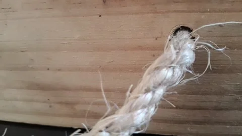 Thick white braided rope pulling through wooden hole motion video Stock Footage 339811167