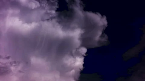 A thick white cloud swirls slowly in the dark blue sky and floats away. Video stock 142081031