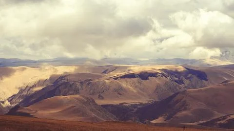 Thick white clouds hung over the Caucasian mountain valley, and the rays of the Stock Photos