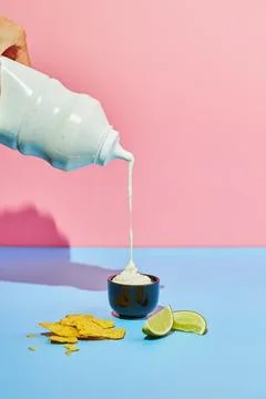 Thick white mayonnaise, ranch or garlic sauce is poured from a bottle into .. Stock Photos